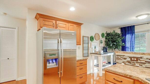 A kitchen with wooden cabinets, a stainless steel refrigerator, a granite countertop, and a potted plant. - Virginia Escape w/ Patio & Fire Pit, Near Hiking! (Wytheville)