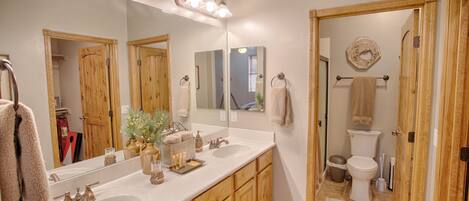 Une salle de bain avec deux lavabos, un grand miroir et des meubles en bois.