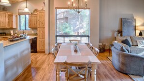 Een ruime keuken met houten kastjes, een eethoek met tafel en stoelen, en een gezellige woonkamer met een bank en een open haard.
