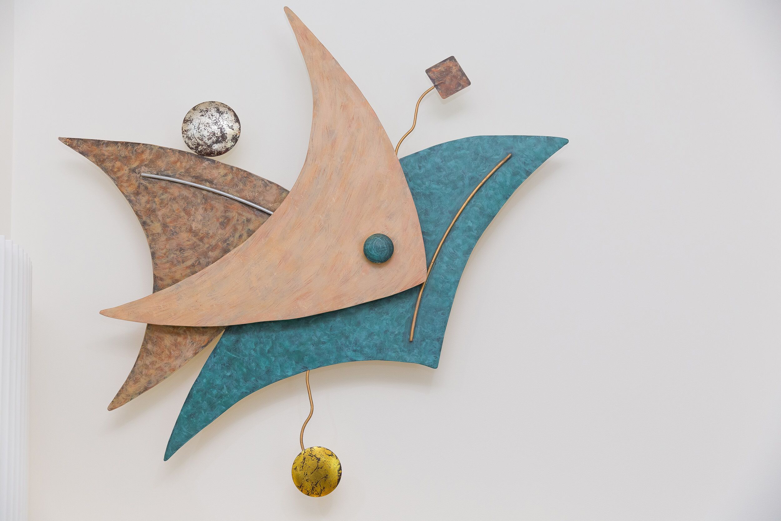 A wall-mounted abstract art piece with geometric shapes and a hanging element.