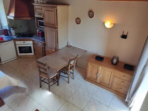 Une cuisine compacte avec une table à manger, des placards en bois et un four encastré.