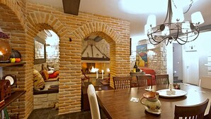 Un comedor acogedor con chimenea de piedra, mobiliario de madera y una araña.