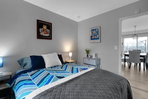 Une chambre moderne avec un grand lit, des tables de chevet, un bureau et un coin repas avec des chaises.