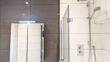 Une salle de bain moderne avec une douche à parois de verre, un grand miroir et un porte-serviettes.
