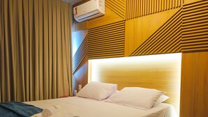 A hotel room with a large bed, a wooden headboard, and a ceiling-mounted air conditioner. - Edifício Time (Maceió)