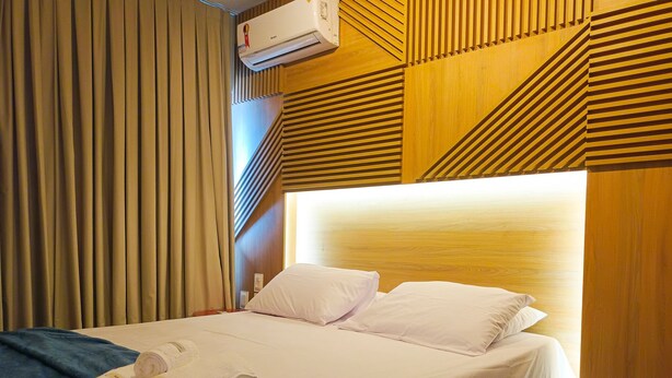 A hotel room with a large bed, a wooden headboard, and a ceiling-mounted air conditioner. - Edifício Time (Maceió)
