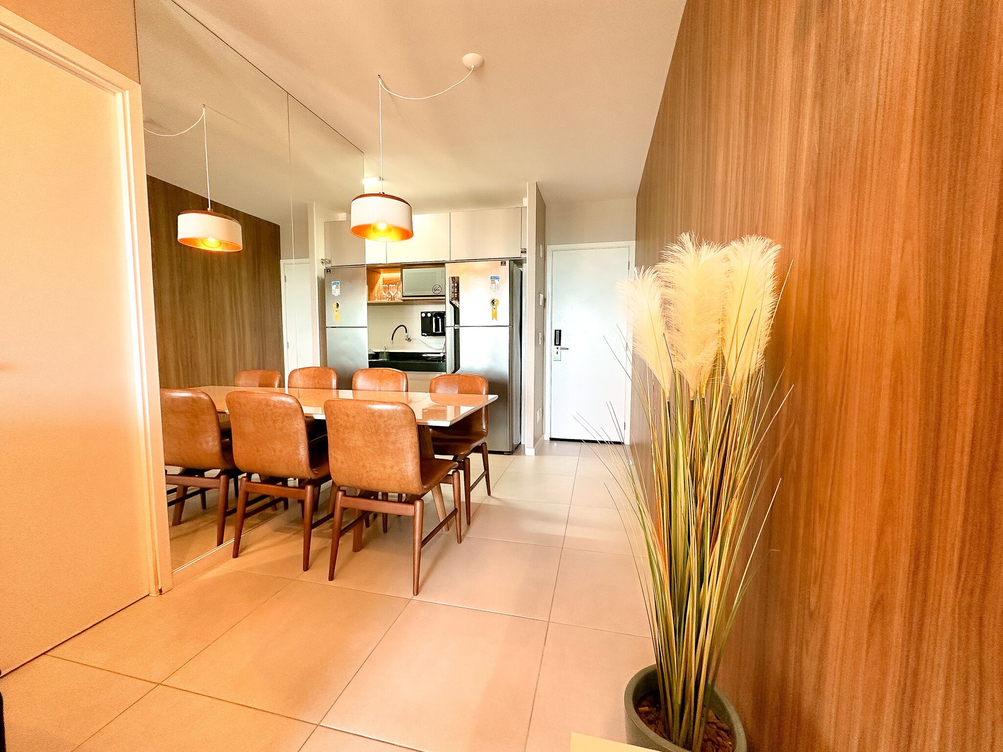 Una cocina moderna con electrodomésticos de acero inoxidable, un comedor con una mesa y sillas de madera, y una planta decorativa.