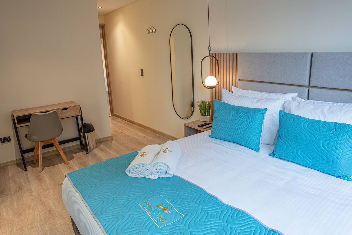 A hotel room with a bed, a desk, and a chair.