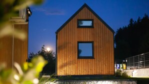 A wooden cabin with a triangular roof and two windows.