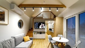 A modern interior with a sofa, dining table, chairs, a kitchen area, and a staircase.