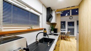 A modern kitchen with a built-in sink, a stove, and a window with blinds.