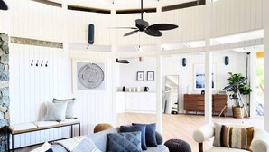 Un salon moderne avec un canapé d’angle, un banc et un coin repas à l’arrière-plan.