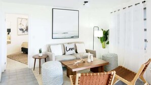 Un salon moderne avec un canapé, une table basse et des fauteuils en osier.