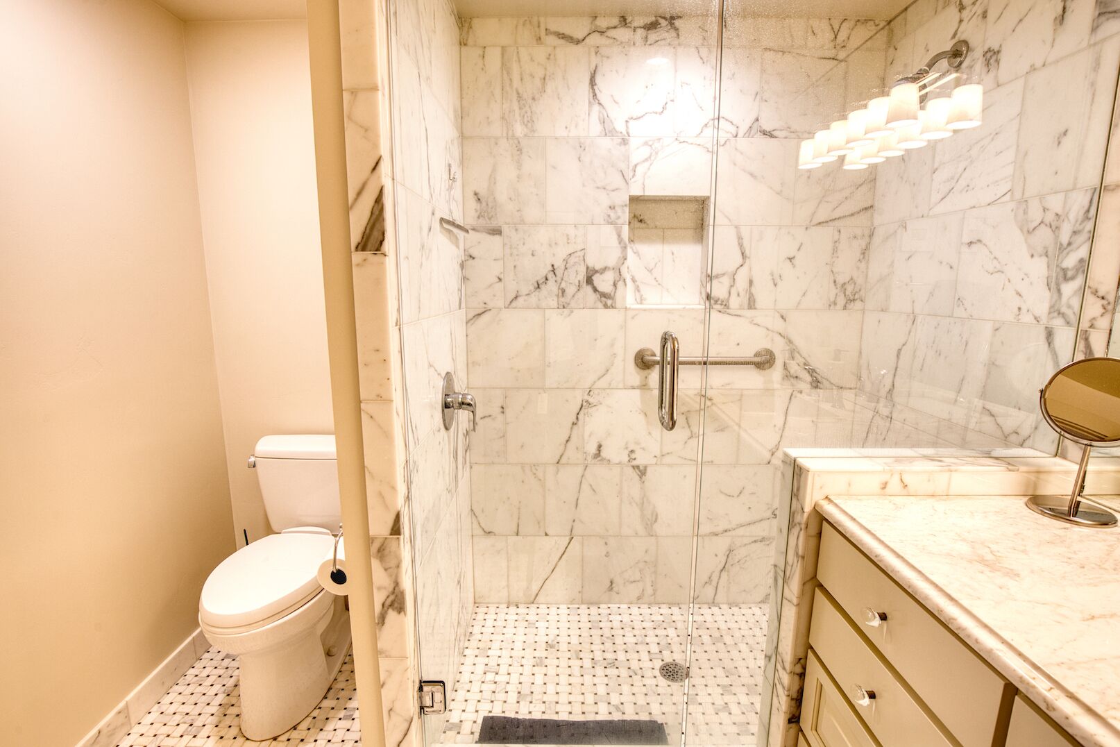 A bathroom with a toilet, a shower with a glass door, and a vanity with a mirror.