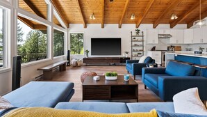 A spacious living area with a large TV, wooden ceiling, and a view of the outdoors.