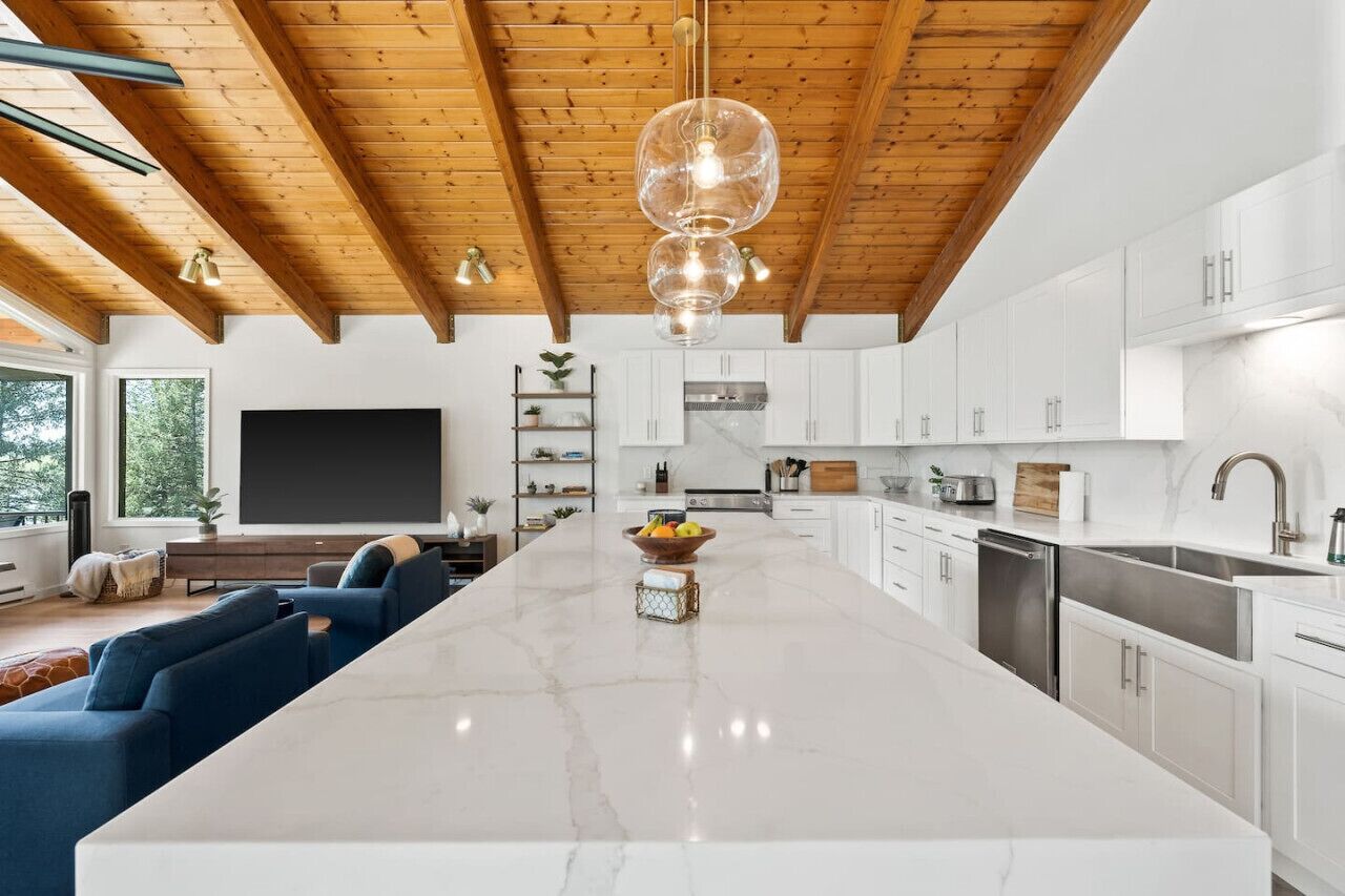 Una cocina moderna con armarios blancos, una isla de mármol e iluminación colgante.
