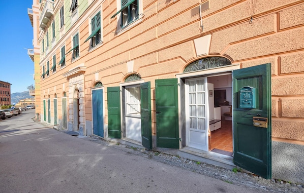 A row of traditional European-style buildings with green shutters and a clear blue sky.