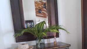 Un aparador antiguo verde con un espejo encima, un pequeño florero con una planta y un plato decorativo.