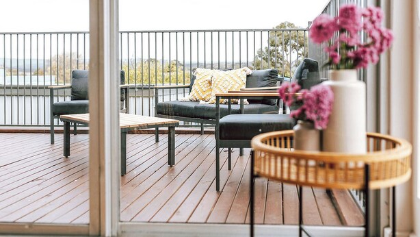 A wooden deck with outdoor furniture, including a sofa and chairs, and a small table. - Wombat Hollow - Holiday Houses Tasmania (Swansea)
