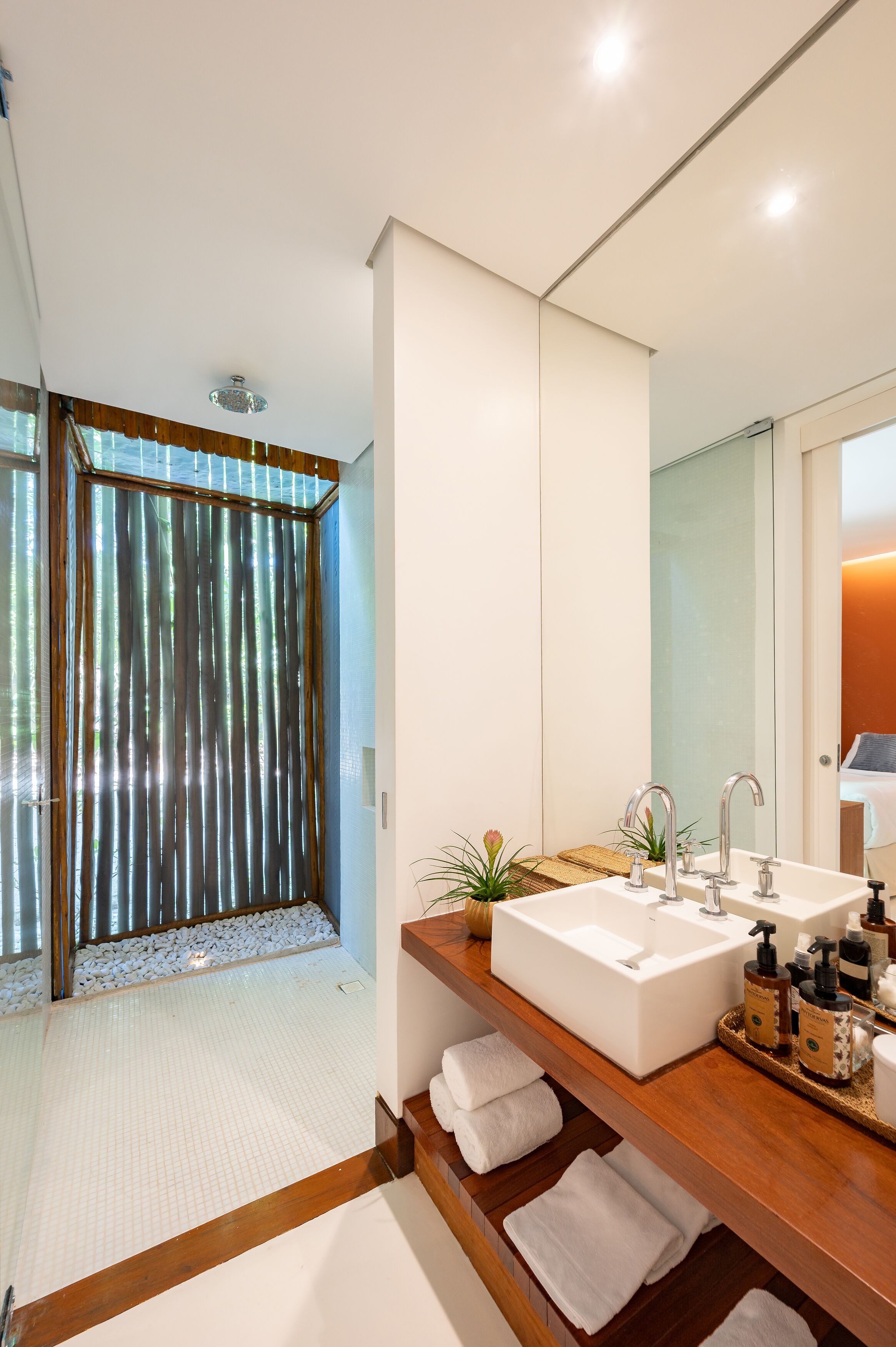 A modern bathroom with a large mirror, two sinks, and a shower area with a glass door.