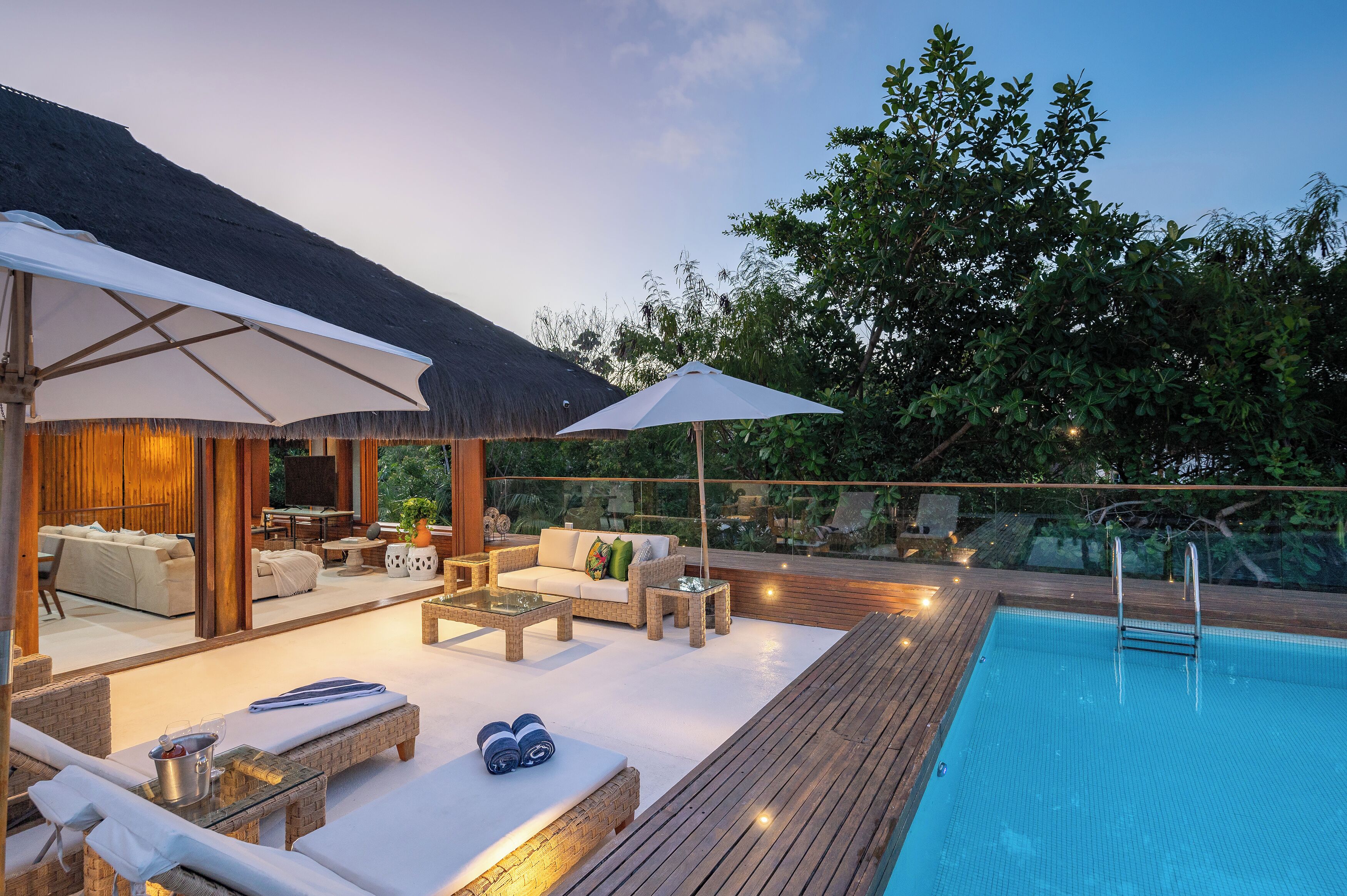 An outdoor pool area with lounge chairs, a sofa, and umbrellas.