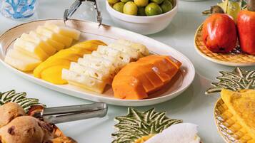 Una mesa servida con diversos platos, incluyendo un pastel Bundt, frutas en rodajas y un bol de aceitunas.