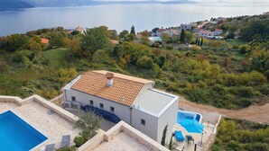 A modern villa with a swimming pool, surrounded by lush greenery and a view of a large body of water. - Villa Soleil in peaceful location with a sea view (Mali Kosi)
