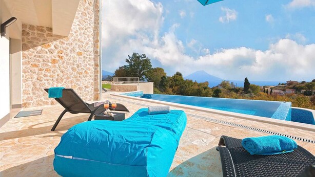 A poolside area with a stone wall, lounge chairs, and a view of a mountain. - Villa Soleil in peaceful location with a sea view (Mali Kosi)