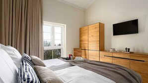 A bedroom with two beds, a wooden wardrobe, a TV, and a window with curtains. - Angel Marie Villa in a calm location with sea-view (Veli Kosi)