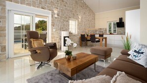 A spacious living area with a stone wall, a dining table, and a sofa. - Angel Marie Villa in a calm location with sea-view (Veli Kosi)