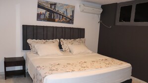 A bedroom with a bed, a nightstand, a painting on the wall, and an air conditioning unit. - Hotel Inambu (Villavicencio)