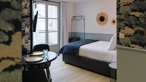 A modern bedroom with a bed, bedside table, and a window with curtains. - Le Logis d'Origine. (Marly-le-Roi)