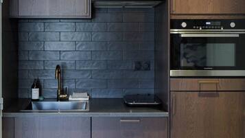 A modern kitchen with dark wood cabinets, a black brick backsplash, and stainless steel appliances.