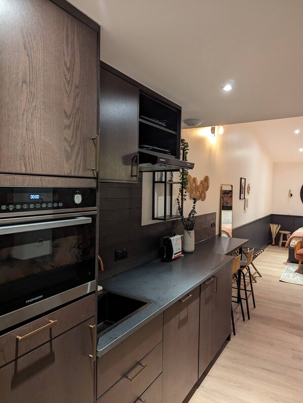 Una cocina moderna con armarios de madera oscura, horno empotrado y campana extractora de acero inoxidable.