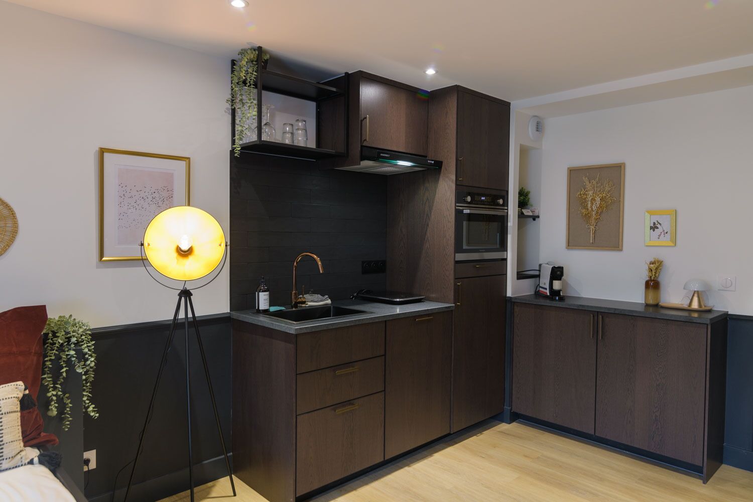 A modern kitchen with dark wood cabinets, a built-in oven, and a countertop with a sink.