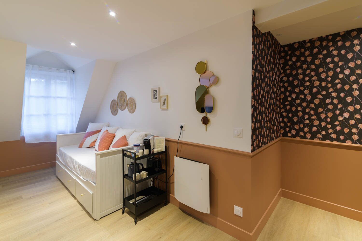 A bedroom with a bed, a radiator, a shelf with items, and a wall with decorative plates.
