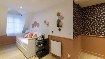 A bedroom with a bed, a radiator, a shelf with items, and a wall with decorative plates.