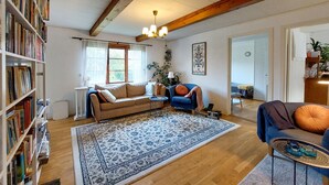 A cozy living room with a sofa, armchairs, a coffee table, and a bookshelf.