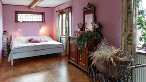 A bedroom with a bed, wooden dresser, and a wicker basket.