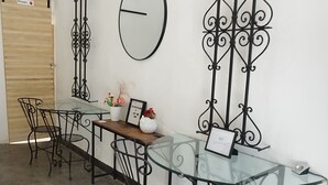 A conference room with a glass table, metal chairs, a clock, and decorative metalwork on the wall. - DGM Lofts MTY C (Monterrey)