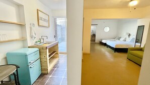 A modern hotel room with a kitchenette, a bathroom, a bed, and a small seating area. - DGM Lofts MTY C (Monterrey)