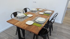 A dining table set with white plates, clear glasses, and cutlery, surrounded by black chairs.