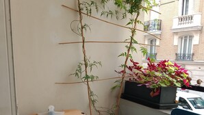 A balcony with a potted plant, a small table, and a chair. - Paris, à 6mn de St Lazare, au Pied de la Gare, F3 Neuf, 7 Couchages max (Asnières sur Seine)