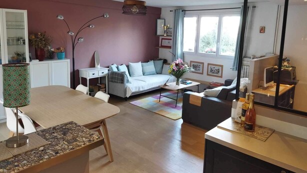A modern living room with a sofa, a dining table, and a coffee table. There is a mirror, a lamp, and a window with curtains. - Paris, à 6mn de St Lazare, au Pied de la Gare, F3 Neuf, 7 Couchages max (Asnières sur Seine)
