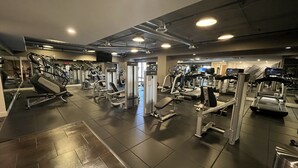 A gym with various exercise equipment, including treadmills and weight machines, arranged in a spacious layout.
