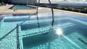 A clear swimming pool with a metal ladder and a view of mountains in the background.