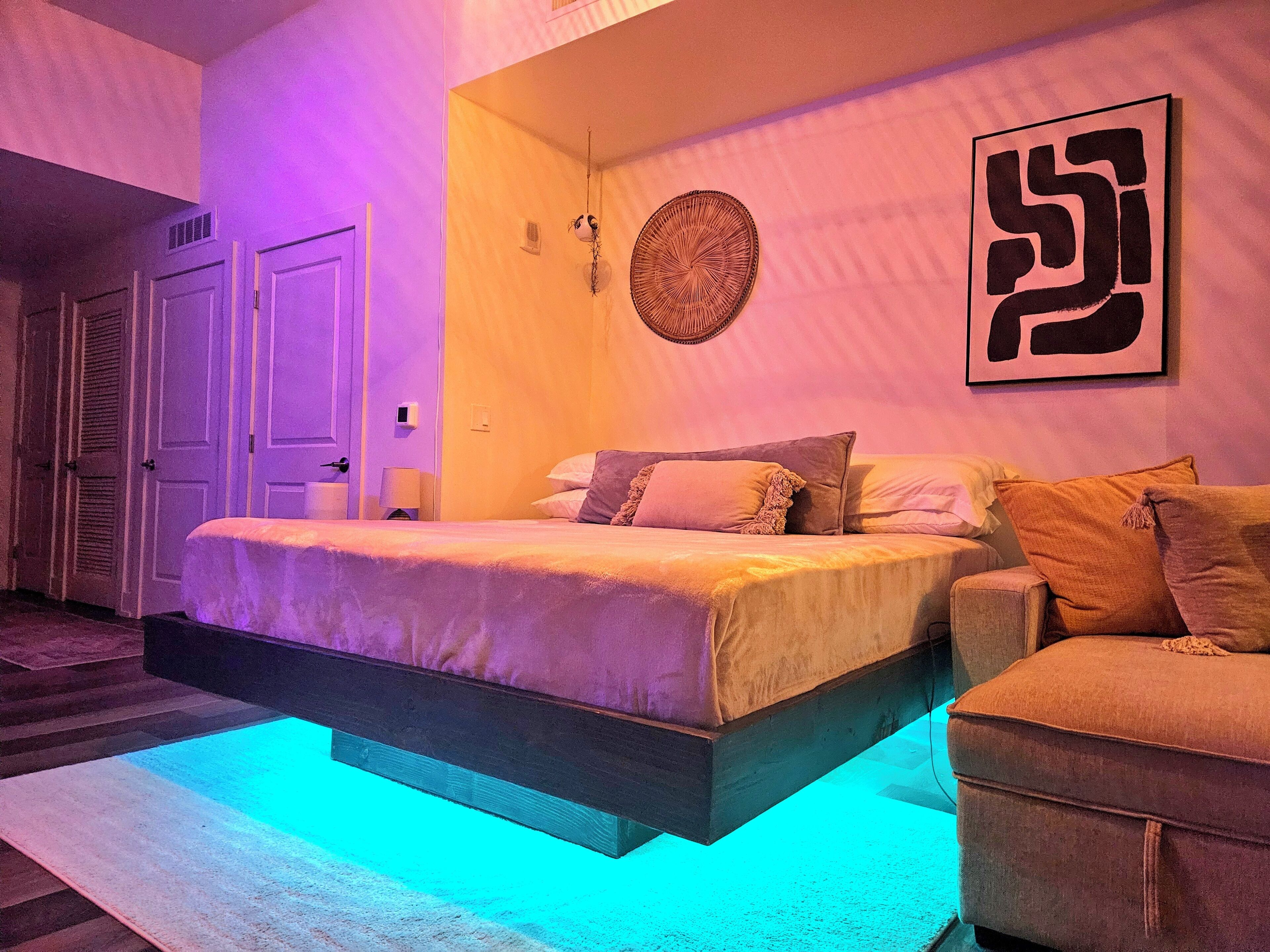 Un dormitorio con cama, una silla, una obra de arte en la pared y una puerta.