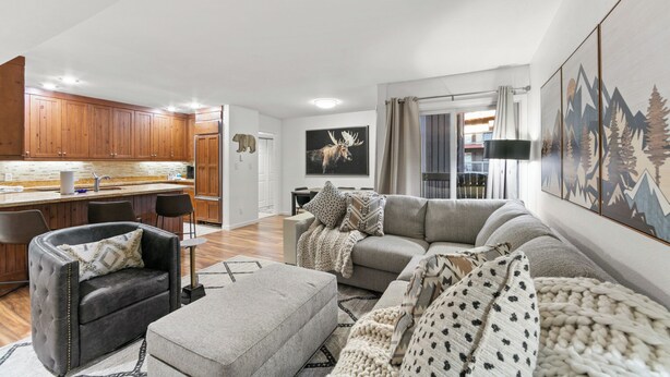 A modern living room with a grey sofa, a black armchair, and a wooden kitchen in the background. - Wi1073-2 (Keystone)