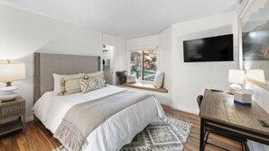 A bedroom with a bed, bedside table, lamp, and a TV mounted on the wall. - Wi1073-2 (Keystone)