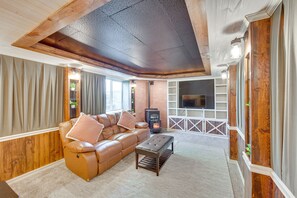 Cozy living room with a brick fireplace, flat-screen TV, and comfortable leather sofa.